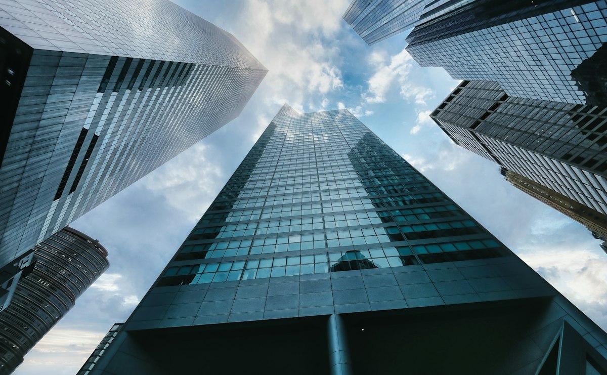 Immeuble de grande hauteur sous les nuages, illustrant la transmission via une holding