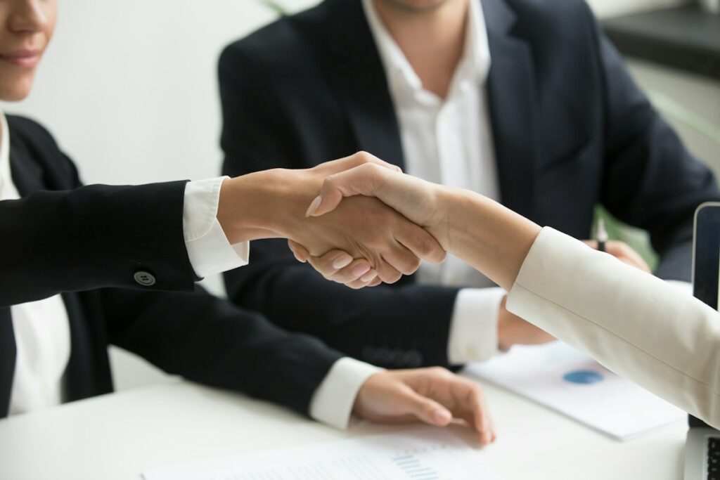 Poignée de main devant un ordinateur portable scellant un accord de rachat d'entreprise par LBO